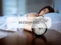 Kobieta leży w łóżku, obok budzik. Tekst "BEZSENNOŚĆ" sugeruje, jak walczyć z bezsennością i odzyskać spokojny sen.