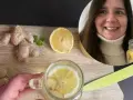 Kobieta przygotowuje orzeźwiającą wodę z imbirem i cytryną. Na desce leżą świeże korzenie imbiru i plaster cytryny.