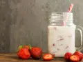Kefir z truskawkami w słoiku, obok świeże owoce. Niska wartość indeksu glikemicznego sprawia, że to zdrowa przekąska.
