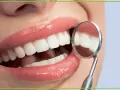 Biała dieta po wybielaniu zębów? Uśmiech jak z reklamy, lśniące zęby odbijają się w lusterku dentystycznym.