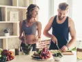 Para dieta 3000 kcal jadłospis tygodniowy, para przygotowuje zdrowe posiłki. Ona miesza sałatkę, on kroi warzywa.