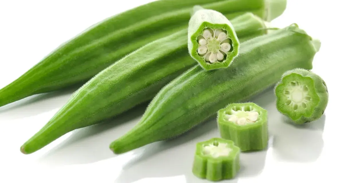 Kilka zielonych strąków okry, w tym przekrojone, ukazujące nasiona. Okra po polsku to pyszny dodatek do dań.