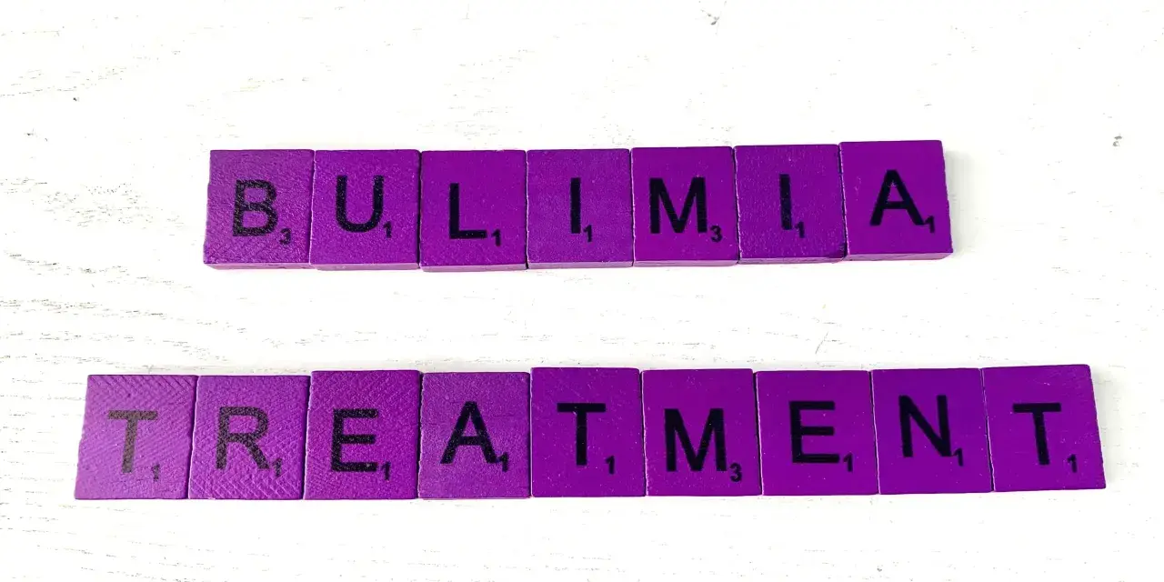 Fioletowe kafelki z literami układają słowa "BULIMIA TREATMENT". Bulimia co to? Leczenie jest kluczowe.