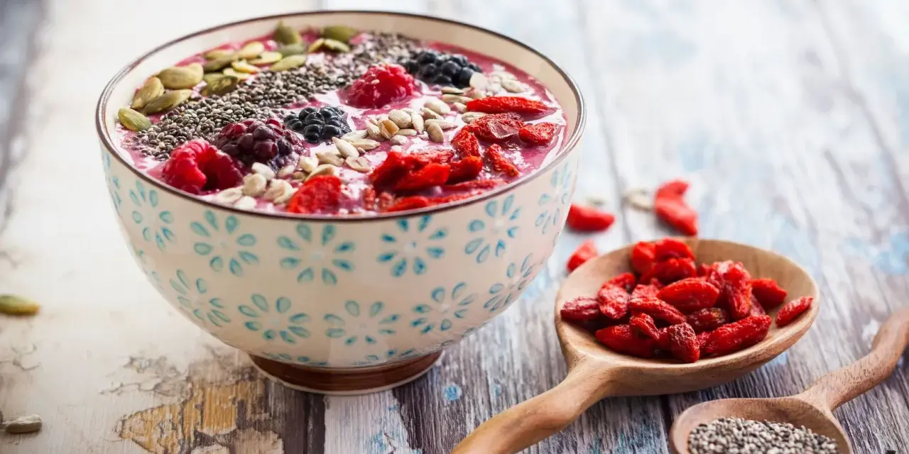 Miseczka smoothie z owocami i nasionami. Nasiona chia, jagody, maliny, pestki dyni i słonecznika. Niski indeks glikemiczny.