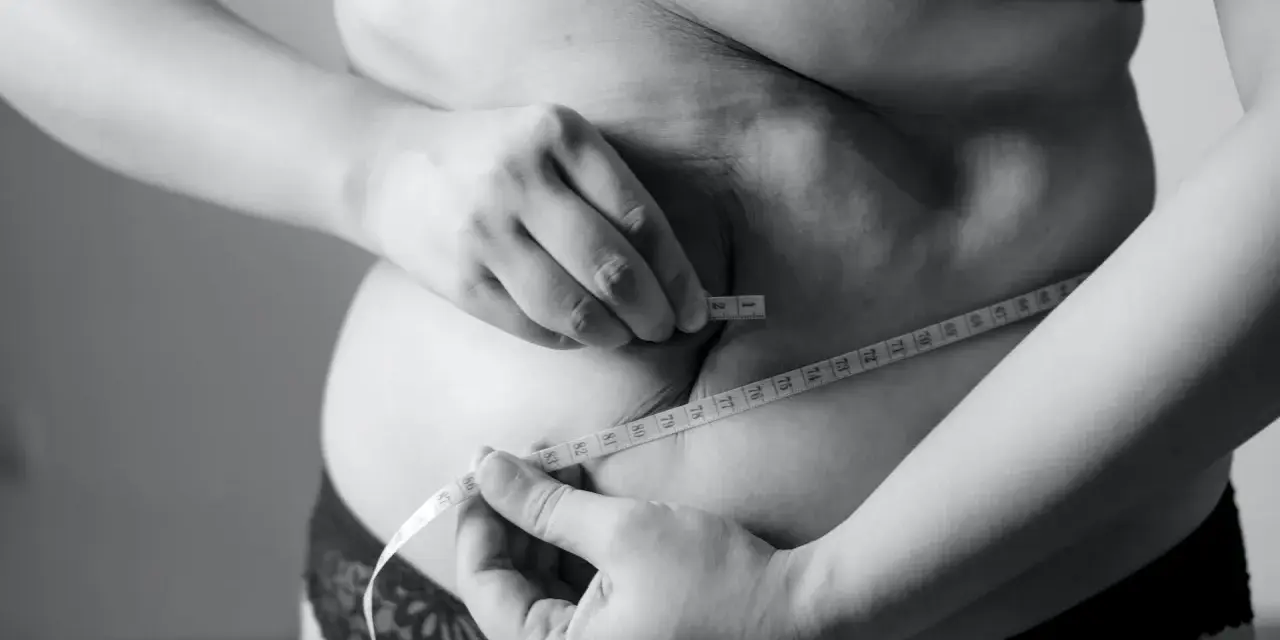 Kobieta mierzy talię centymetrem, szukając sposobu, jak schudnąć 5 kg w 3 dni.