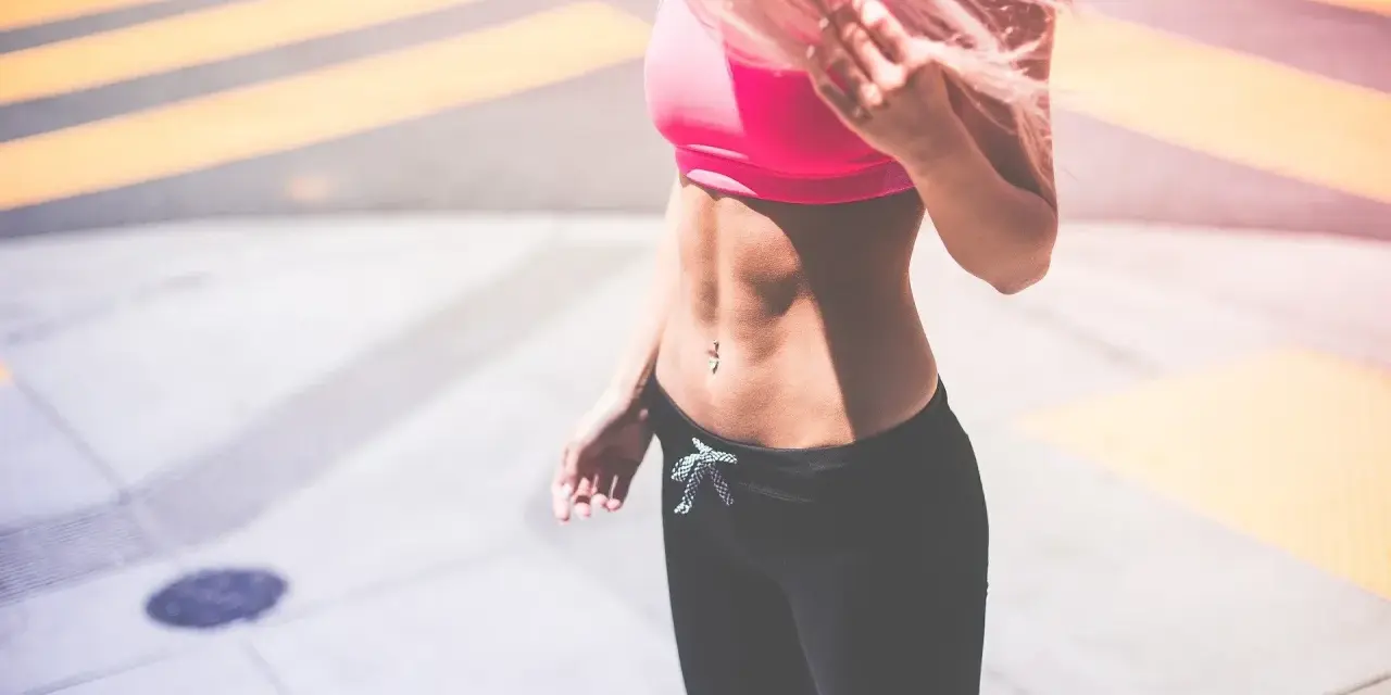 Kobieta z różowymi włosami w sportowym topie i legginsach. Zastanawiasz się, co jeść, żeby przytyć 10 kg?