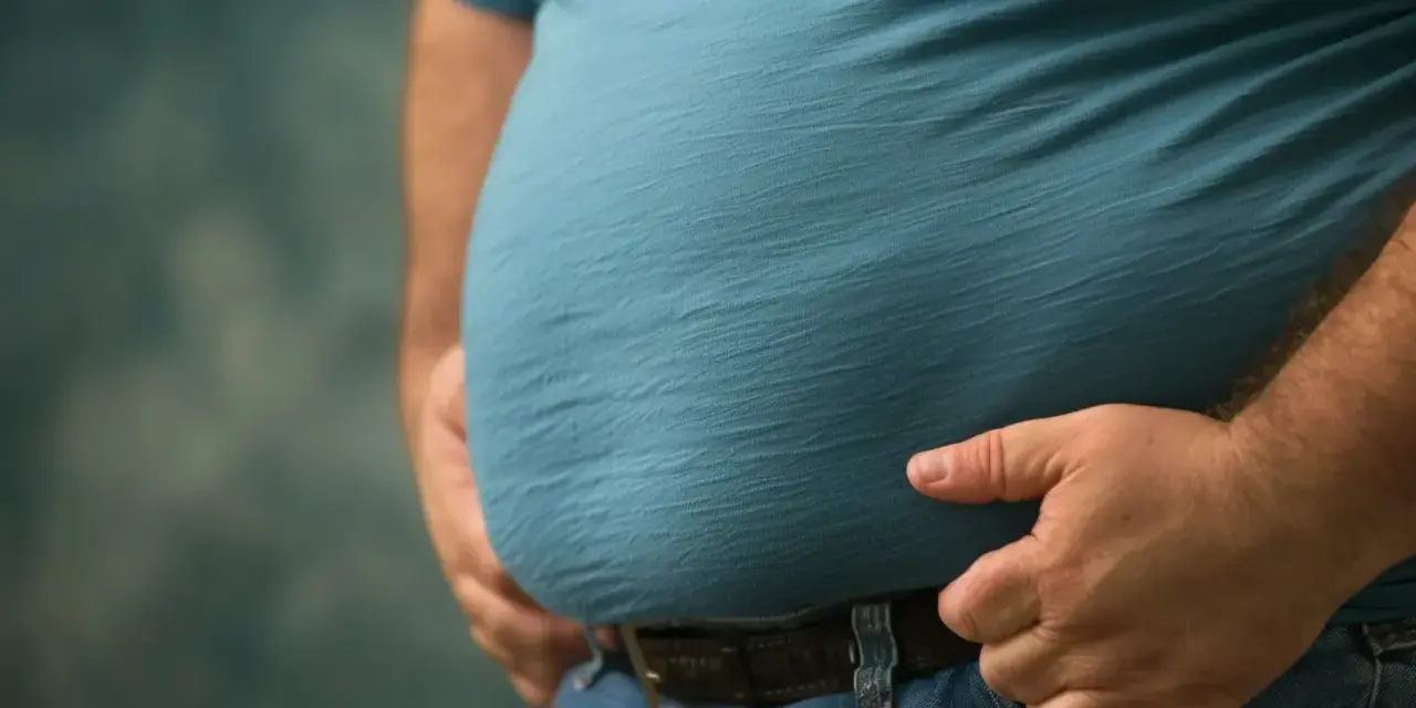 Mężczyzna z widocznym brzuchem, symbolizującym problemy zdrowotne, takie jak zespół metaboliczny. Dieta jest kluczowa w walce z tym schorzeniem.