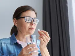 Kobieta w okularach bierze tabletkę, zastanawiając się nad mysimba skutki uboczne.