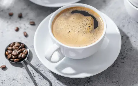 Aromatic coffee in a white cup, with beans on a spoon. Czy kawa jest lekkostrawna? To zależy od sposobu parzenia.