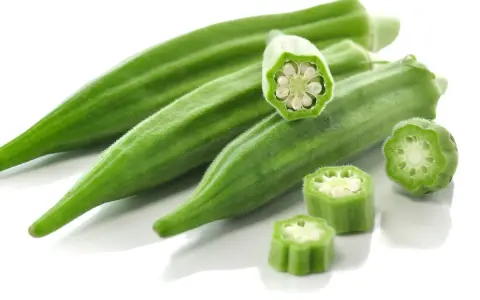 Kilka zielonych strąków okry, w tym przekrojone, ukazujące nasiona. Okra po polsku to pyszny dodatek do dań.