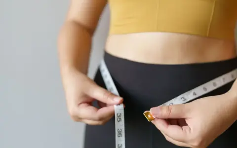 Kobieta mierzy talię centymetrem. Dowiedz się, jak podkręcić metabolizm po 40. i odzyskać formę.