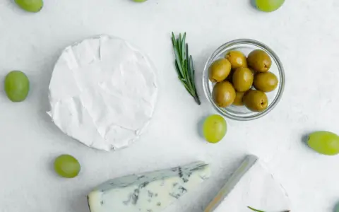 Ser brie, pleśniowy i winogrona otaczają miseczkę z oliwkami. Czy oliwki są lekkostrawne?