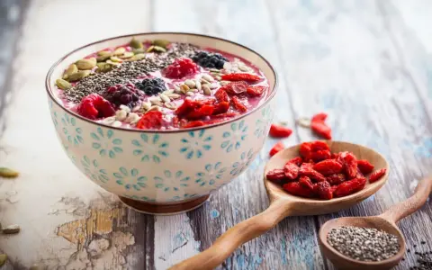 Miseczka smoothie z owocami i nasionami. Nasiona chia, jagody, maliny, pestki dyni i słonecznika. Niski indeks glikemiczny.
