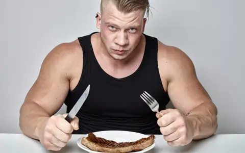 Mięśniak z determinacją wpatruje się w stek, gotowy na wyzwanie, jak szybko przytyć.