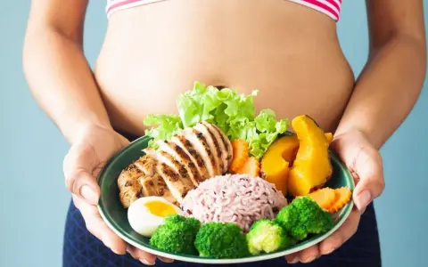 Zdrowa dieta to klucz do tego, jak zgubić oponkę z brzucha. Na talerzu grillowany kurczak, ryż, jajko i warzywa.