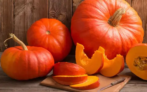 Pomarańczowe dynie, w tym połówka i kawałki na desce, przypominają o ich bogactwie witamin i cennych właściwościach zdrowotnych.