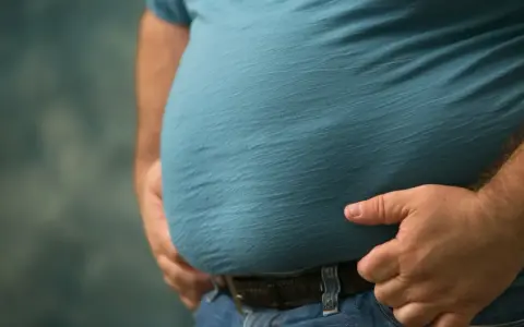 Mężczyzna z widocznym brzuchem, symbolizującym problemy zdrowotne, takie jak zespół metaboliczny. Dieta jest kluczowa w walce z tym schorzeniem.