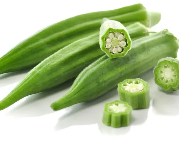 Kilka zielonych strąków okry, w tym przekrojone, ukazujące nasiona. Okra po polsku to pyszny dodatek do dań.