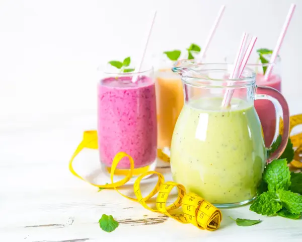Kolorowe smoothie odchudzające przepisy w dzbanku i szklankach, ozdobione miętą i taśmą mierniczą.