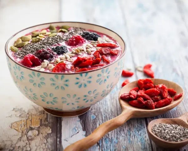 Miseczka smoothie z owocami i nasionami. Nasiona chia, jagody, maliny, pestki dyni i słonecznika. Niski indeks glikemiczny.