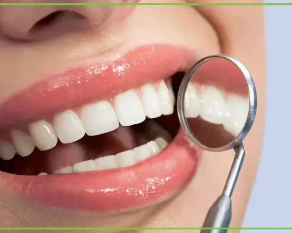 Biała dieta po wybielaniu zębów? Uśmiech jak z reklamy, lśniące zęby odbijają się w lusterku dentystycznym.