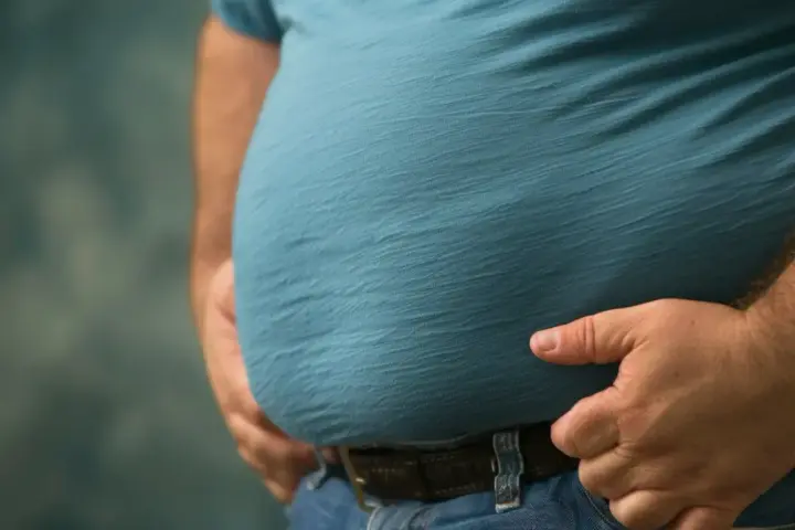 Mężczyzna z widocznym brzuchem, symbolizującym problemy zdrowotne, takie jak zespół metaboliczny. Dieta jest kluczowa w walce z tym schorzeniem.