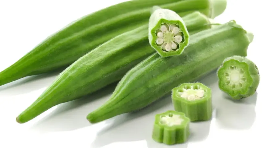 Kilka zielonych strąków okry, w tym przekrojone, ukazujące nasiona. Okra po polsku to pyszny dodatek do dań.