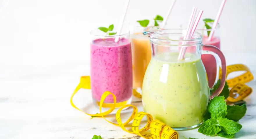 Kolorowe smoothie odchudzające przepisy w dzbanku i szklankach, ozdobione miętą i taśmą mierniczą.