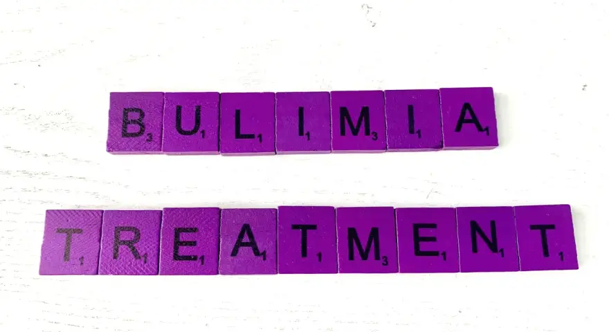Fioletowe kafelki z literami układają słowa "BULIMIA TREATMENT". Bulimia co to? Leczenie jest kluczowe.
