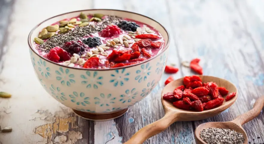 Miseczka smoothie z owocami i nasionami. Nasiona chia, jagody, maliny, pestki dyni i słonecznika. Niski indeks glikemiczny.