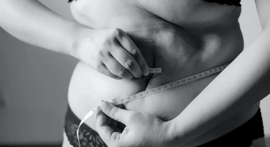 Kobieta mierzy talię centymetrem, szukając sposobu, jak schudnąć 5 kg w 3 dni.
