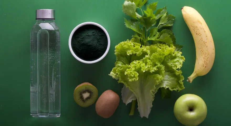 Składniki na japońską dietę wodną: butelka wody, spirulina, kiwi, sałata, seler, banan i jabłko.