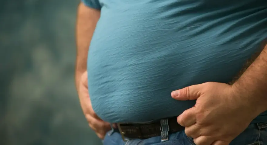 Mężczyzna z widocznym brzuchem, symbolizującym problemy zdrowotne, takie jak zespół metaboliczny. Dieta jest kluczowa w walce z tym schorzeniem.