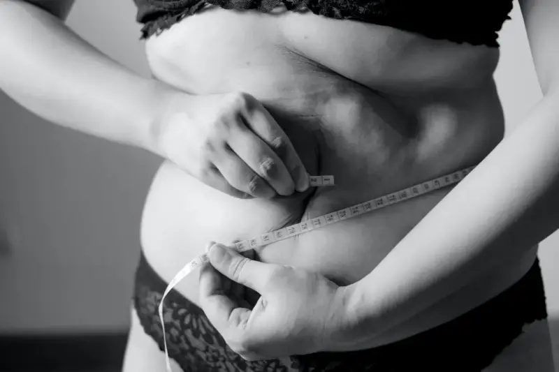 Kobieta mierzy talię centymetrem, szukając sposobu, jak schudnąć 5 kg w 3 dni.